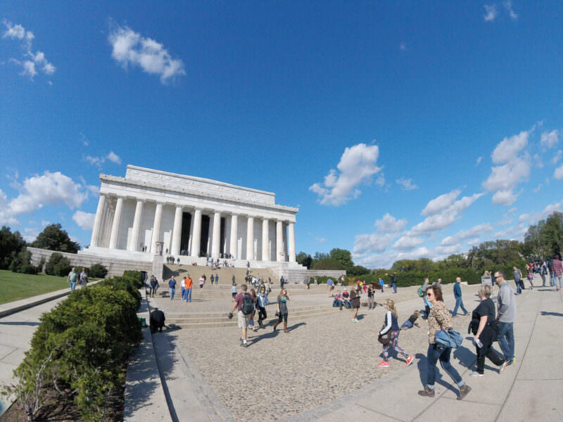 Wide-angle view of the Lincoln Memorial with visitors walking across the plaza on a sunny day