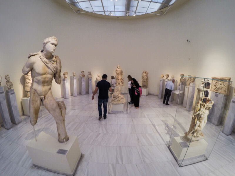 Museum visitors admiring ancient marble statues displayed in a bright gallery in Athens