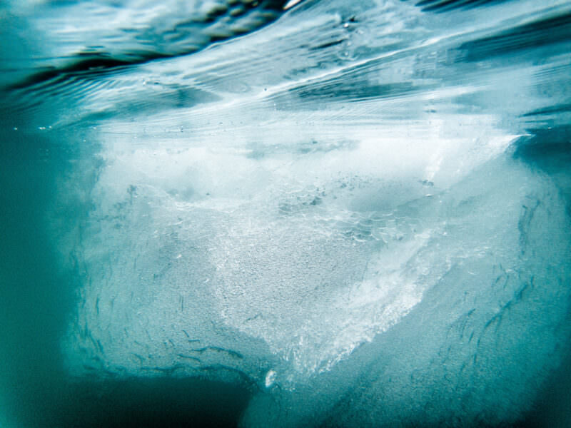 Split view of a small iceberg's submerged edge beneath calm arctic water