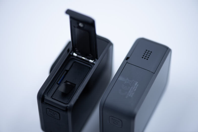 Bottom compartment of the HERO7 Black open to reveal its removable battery and microSD slot, next to the sealed Silver base