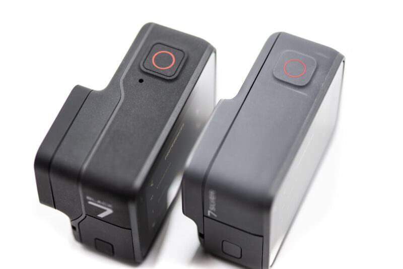 Top view of both HERO7 cameras showing the matching red shutter buttons and the Black's microphone hole