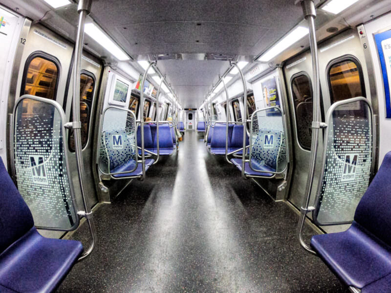 Fisheye view down the aisle of an empty Metro subway car with blue seats