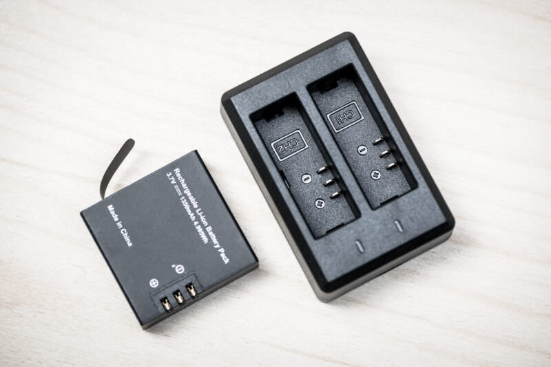 AKASO dual USB battery charger with a spare rechargeable battery pack beside it