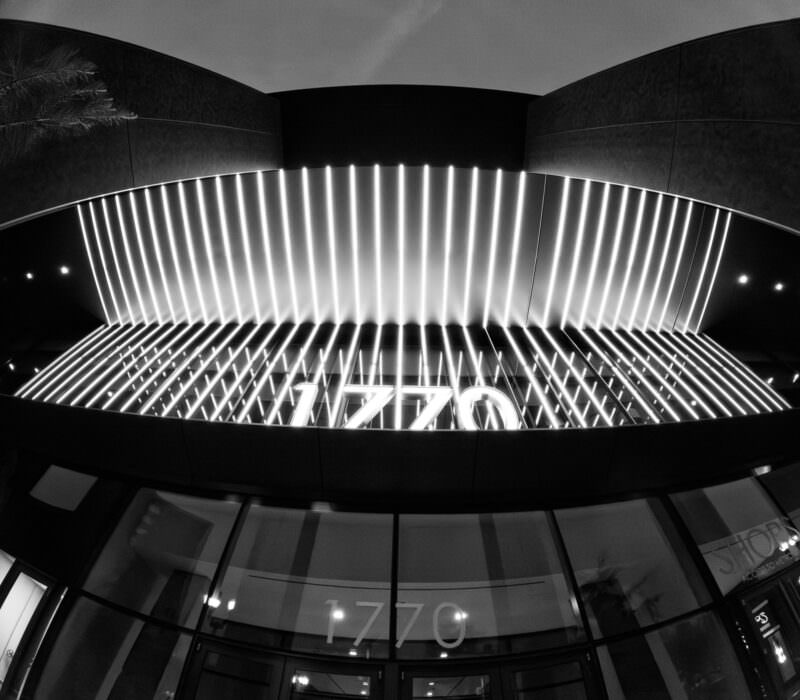 Black-and-white shot of a striped illuminated canopy above a storefront numbered 1770