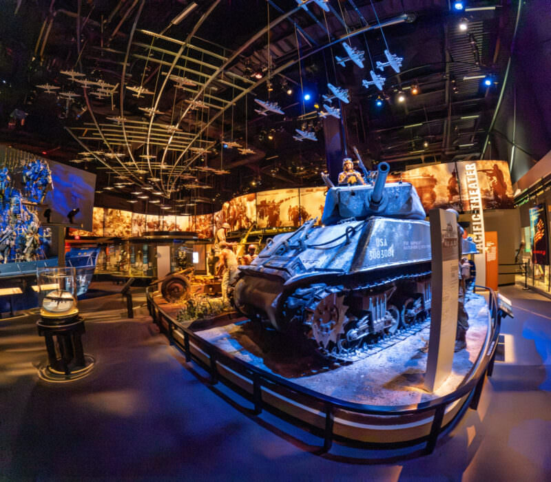 World War II museum exhibit featuring a tank display beneath suspended model aircraft