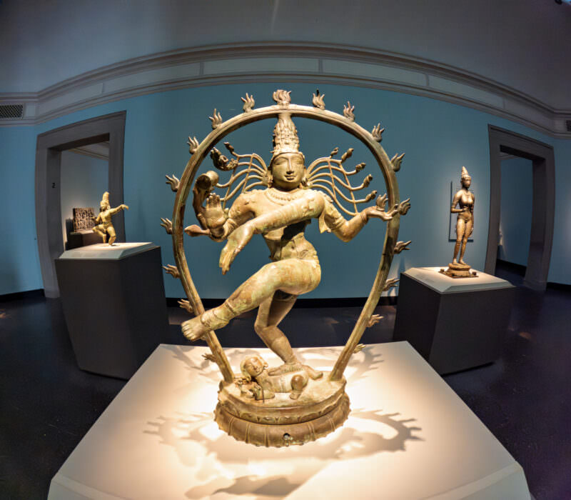Bronze Nataraja statue of Shiva dancing within a ring of flames inside a museum gallery