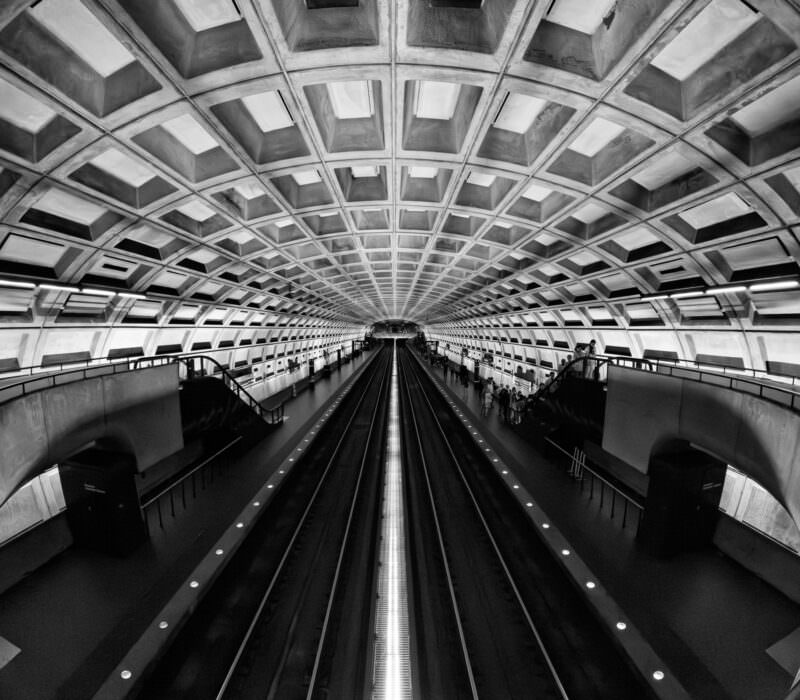 Black-and-white symmetrical view of a Washington DC Metro station platform and tracks