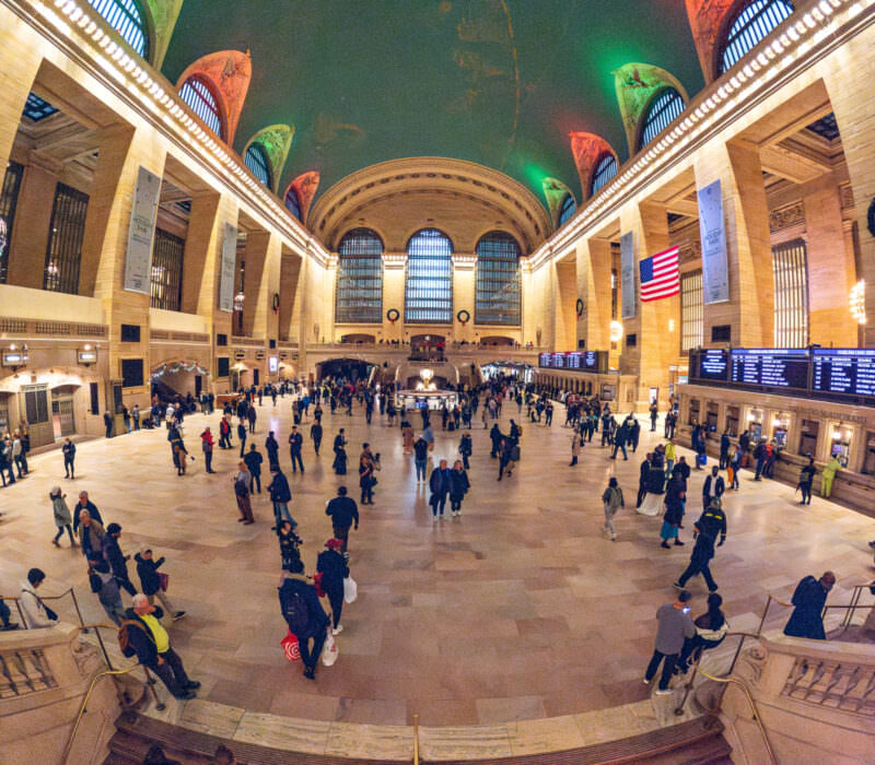 Grand Central Terminal's main concourse crowded with travelers beneath its arched, colorfully lit ceiling