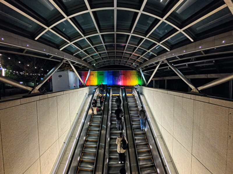 Night sample shot from the Insta360 Ace Pro 2 of an escalator tunnel leading to a rainbow-lit wall