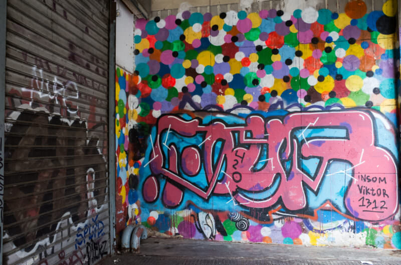 Athens graffiti covering a recessed alcove wall in bright multicolored circles above the pink-and-blue word "LOVE" in bubble letters