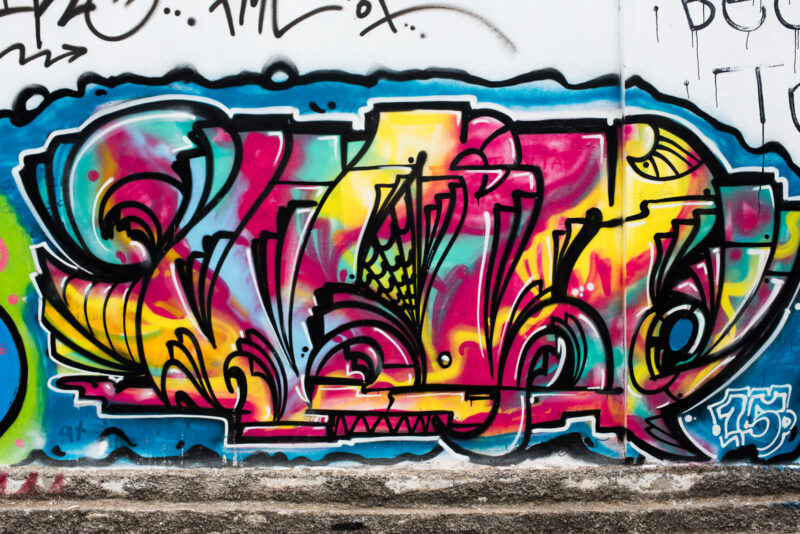 Athens graffiti in bright pink, yellow, and turquoise featuring abstract bubble-letter wildstyle lettering with layered colors