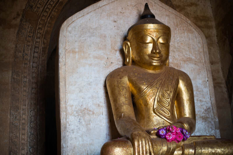 Gilded Buddha in bhumisparsha mudra seated in east shrine of Dhammayangyi Temple beneath ornate barrel-vaulted ceiling