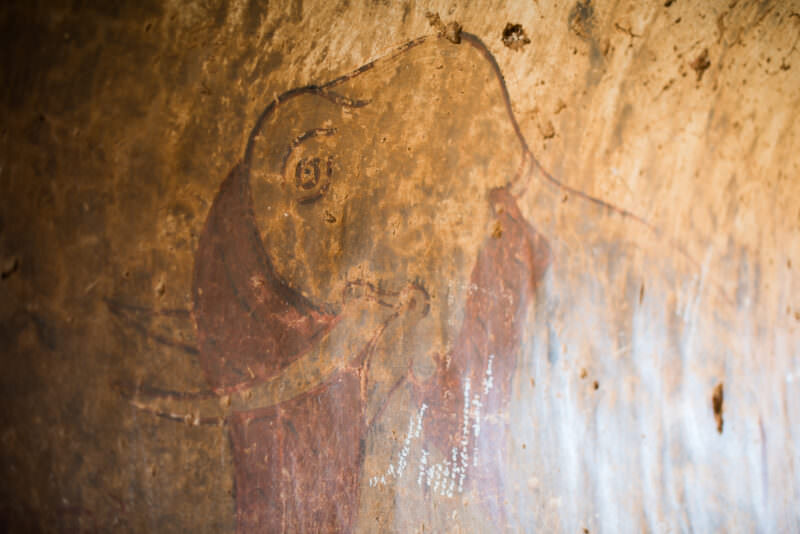 Faded reddish-brown elephant painted on aged plaster wall inside Dhammayangyi Temple, showing weathered pigment and surface cracks