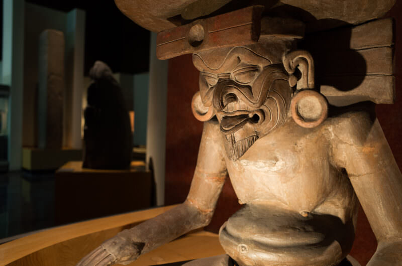 Ceramic Huehuetéotl sculpture, aged fire god supporting brazier on head, displayed on pedestal