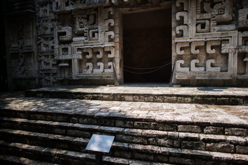 Stone steps leading to Maya replica doorway, facade packed with interlocking hook-and-scroll mosaic carvings