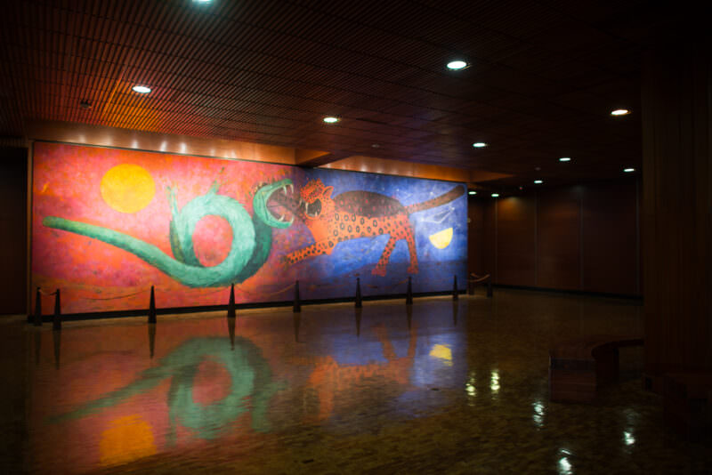 Rufino Tamayo's mural Dualidad, vivid red and blue fields showing green serpent and spotted jaguar under celestial bodies