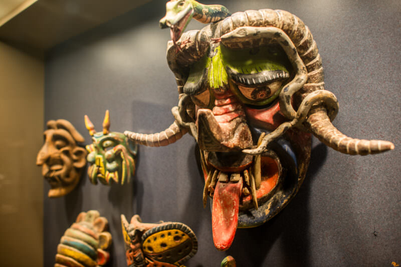 Painted wood ceremonial masks including dominant serpent-entwined devil mask with protruding tongue, from Dance of the Devils tradition