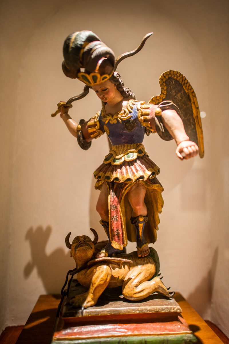 Polychrome wood Archangel Michael sculpture, armored and winged, trampling horned demon underfoot with gold-leaf estofado decoration
