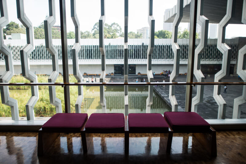 Geometric aluminum celosía screens on upper floor framing view across central courtyard and reflecting pool