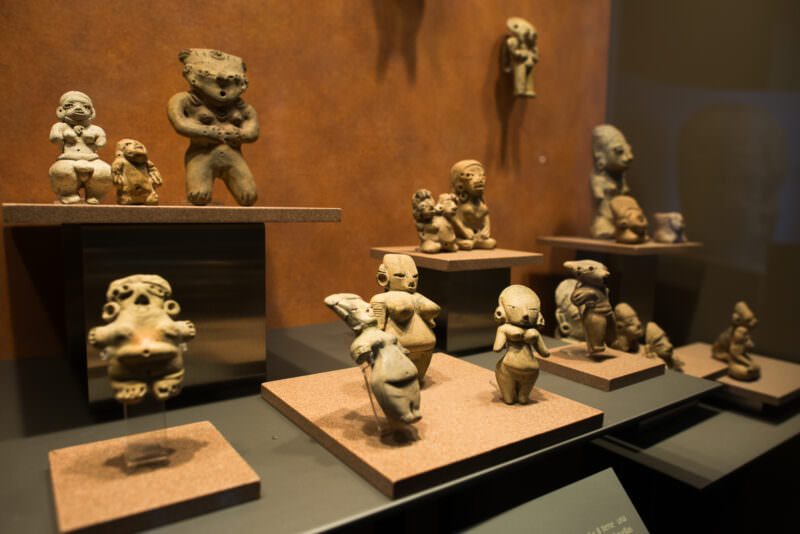 Display case of small pre-Columbian ceramic figurines, most depicting female forms with exaggerated proportions