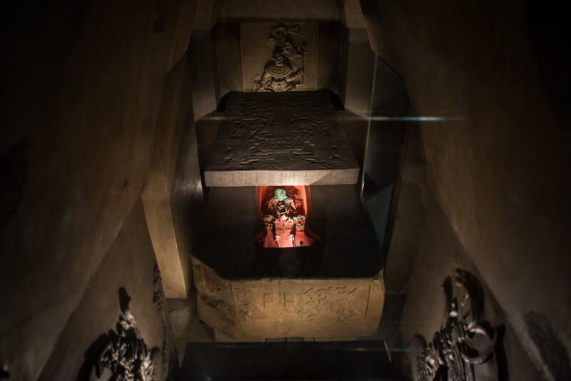 Reconstruction of Pakal's funerary crypt looking down stairway to sarcophagus with massive carved lid partially raised