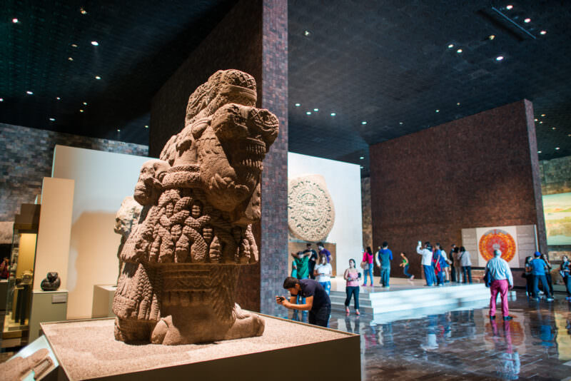 Mexica hall crowded with visitors, Coatlicue statue in foreground, Piedra del Sol on rear wall