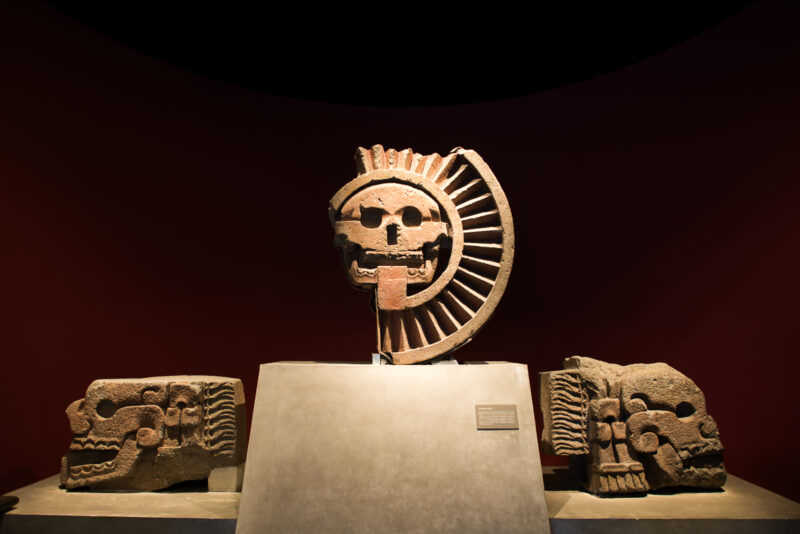 Stone skull within radiating solar disk flanked by two carved skull relief panels in Mexica hall