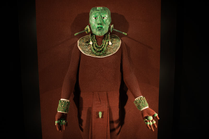 Pakal's jade burial assemblage: mosaic funerary mask of 300+ jade pieces, jade collar, wrist cuffs, and finger rings in display case