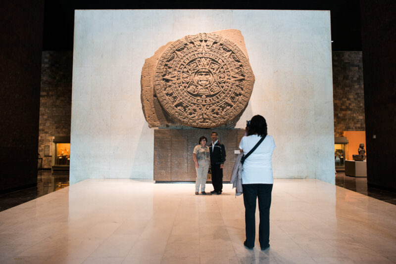 Piedra del Sol (Sun Stone) on display with visitors photographing in front of the monumental carved basalt disc