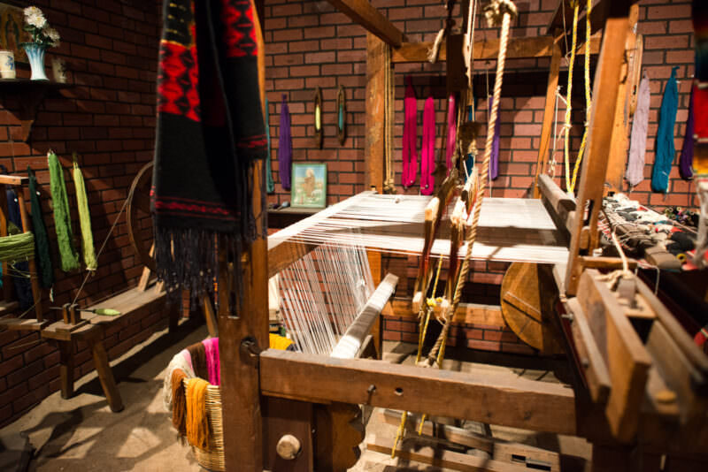 Treadle loom and skeins of dyed wool filling reconstructed weaving workshop representing Tlaxcala textile traditions