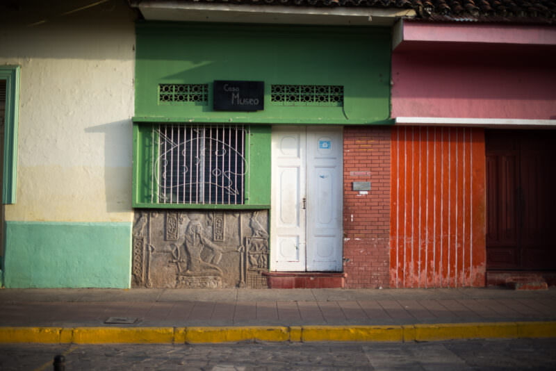 Egyptian-themed bas-relief carving beneath a barred window on a green Casa Museo along Calle La Calzada