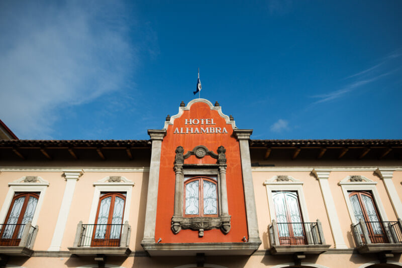 Hotel Alhambra's orange parapet and wrought-iron balconies with exposed wooden roof rafters and terracotta tiles