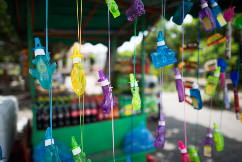 Colorful plastic bubble wands hanging from vendor cart in Parque Central, red-domed bandstand in soft focus behind