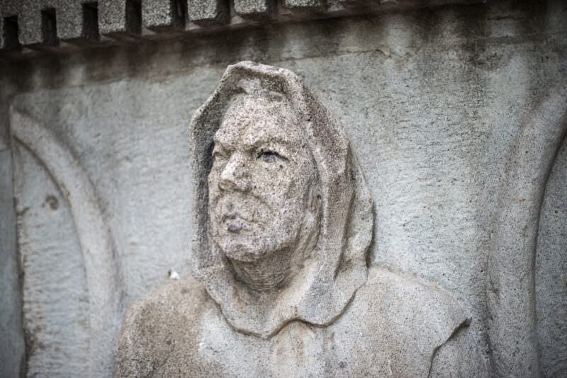 Weathered stone relief of a hooded figure on the Rubén Darío monument base in Parque Central