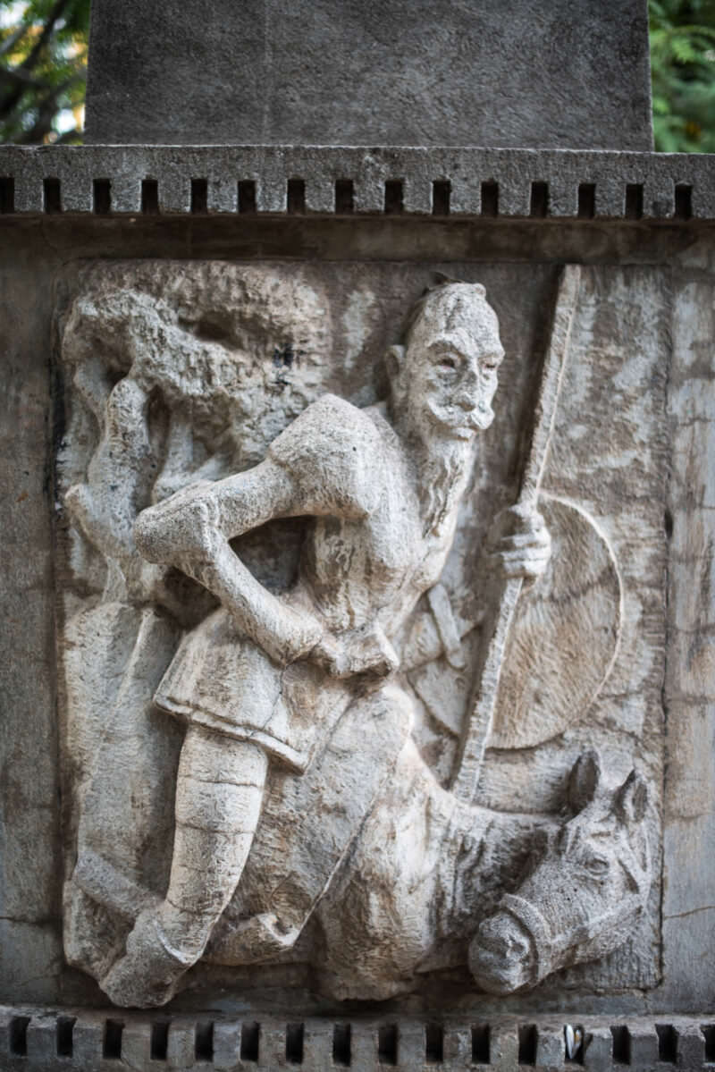 Weathered stone relief of Don Quixote carved into the base of the Rubén Darío Obelisk in Granada