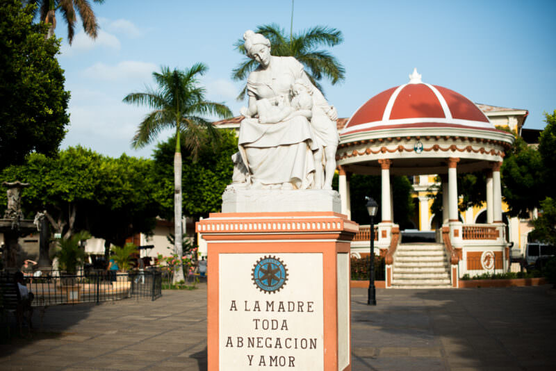 White marble motherhood monument with Rotary emblem, red-domed gazebo and palms visible behind