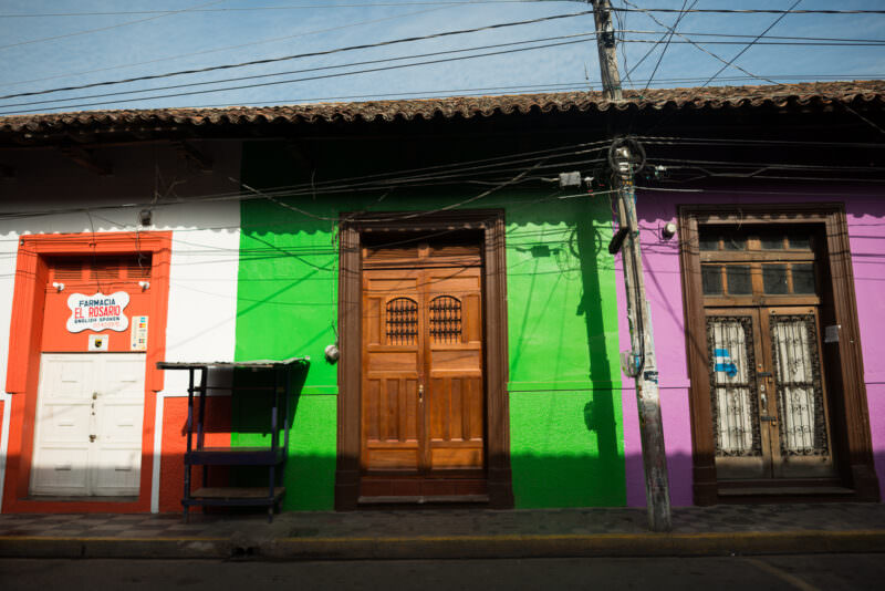 Continuous row of brightly painted colonial facades in orange, green, and purple with terracotta roofs