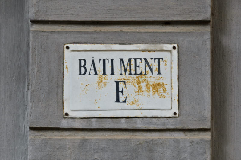 Rusted Batiment E sign on a wall at Hoa Lo Prison