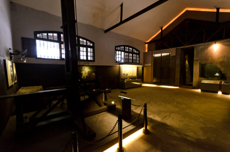 Wooden guillotine standing in an exhibit room near the death row cells at Hoa Lo Prison