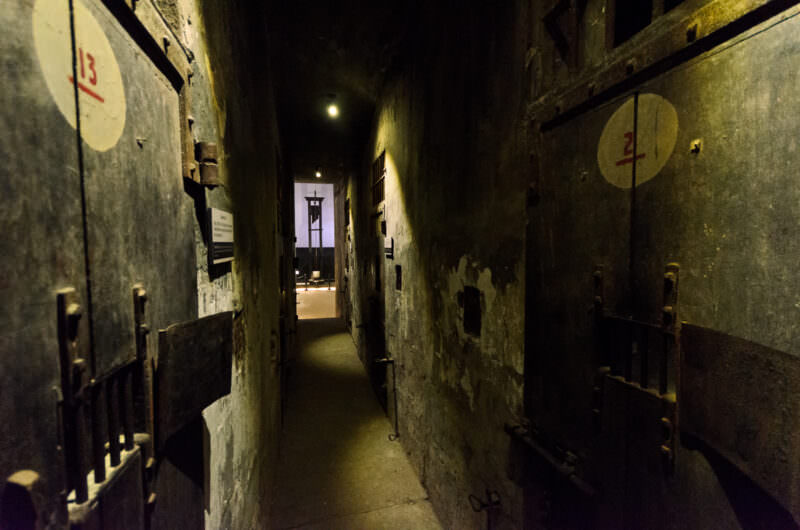 Numbered cell doors along a death row corridor leading to a guillotine at Hoa Lo Prison