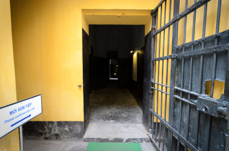 Heavy iron gate opening into a dark corridor at Hoa Lo Prison
