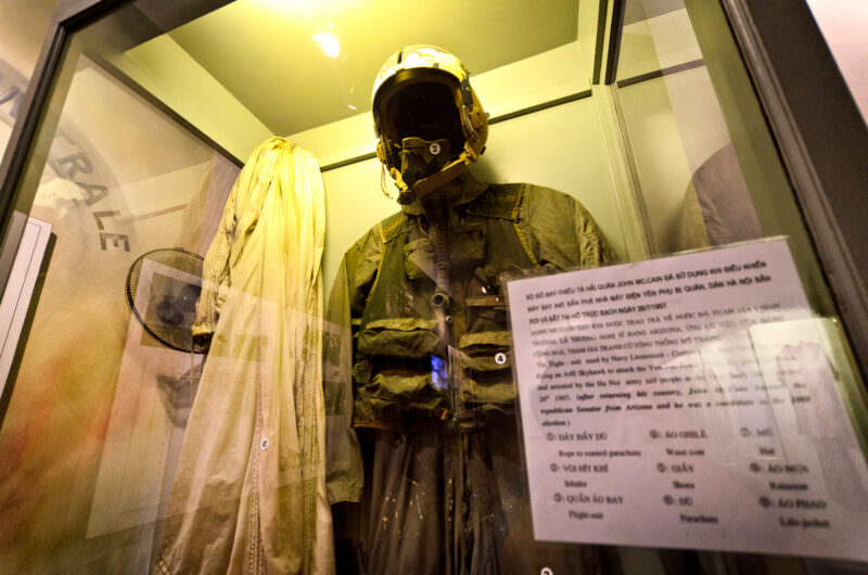 John McCain's flight suit, helmet and parachute displayed in a glass case at the Hanoi Hilton