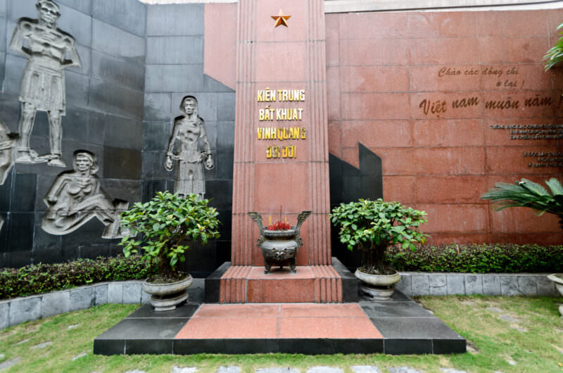 Stone relief and memorial altar honoring political prisoners in the Hoa Lo Prison courtyard