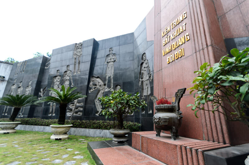 Black stone bas-relief memorial with bronze incense censer in a Hoa Lo Prison courtyard