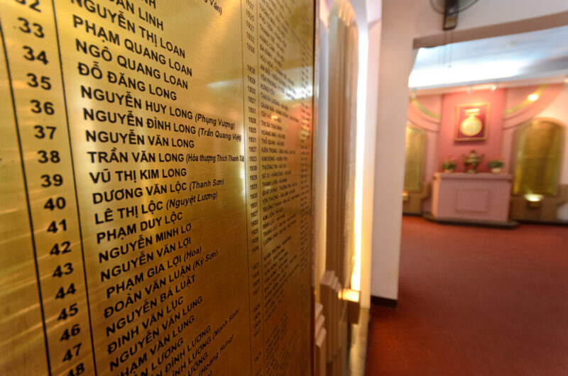 Engraved brass plaque listing Vietnamese inmate names in a Hoa Lo Prison memorial room