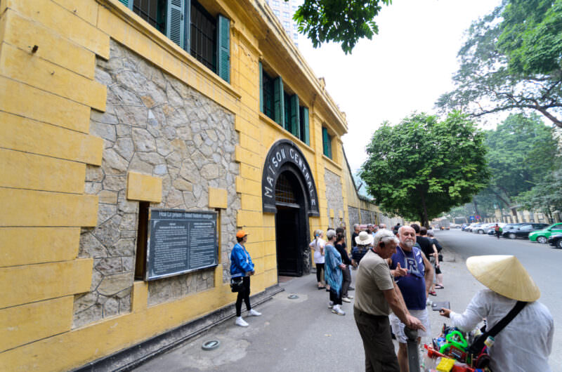 Tourists gathered outside the yellow Maison Centrale entrance of Hoa Lo Prison
