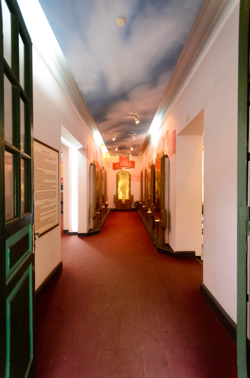 Red-carpeted memorial hall leading to a gold stele inside Hoa Lo Prison