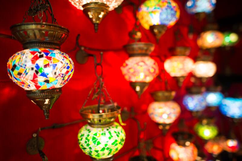 Close-up of mosaic glass lamps in red, green and gold glowing against a red backdrop in a Grand Bazaar shop