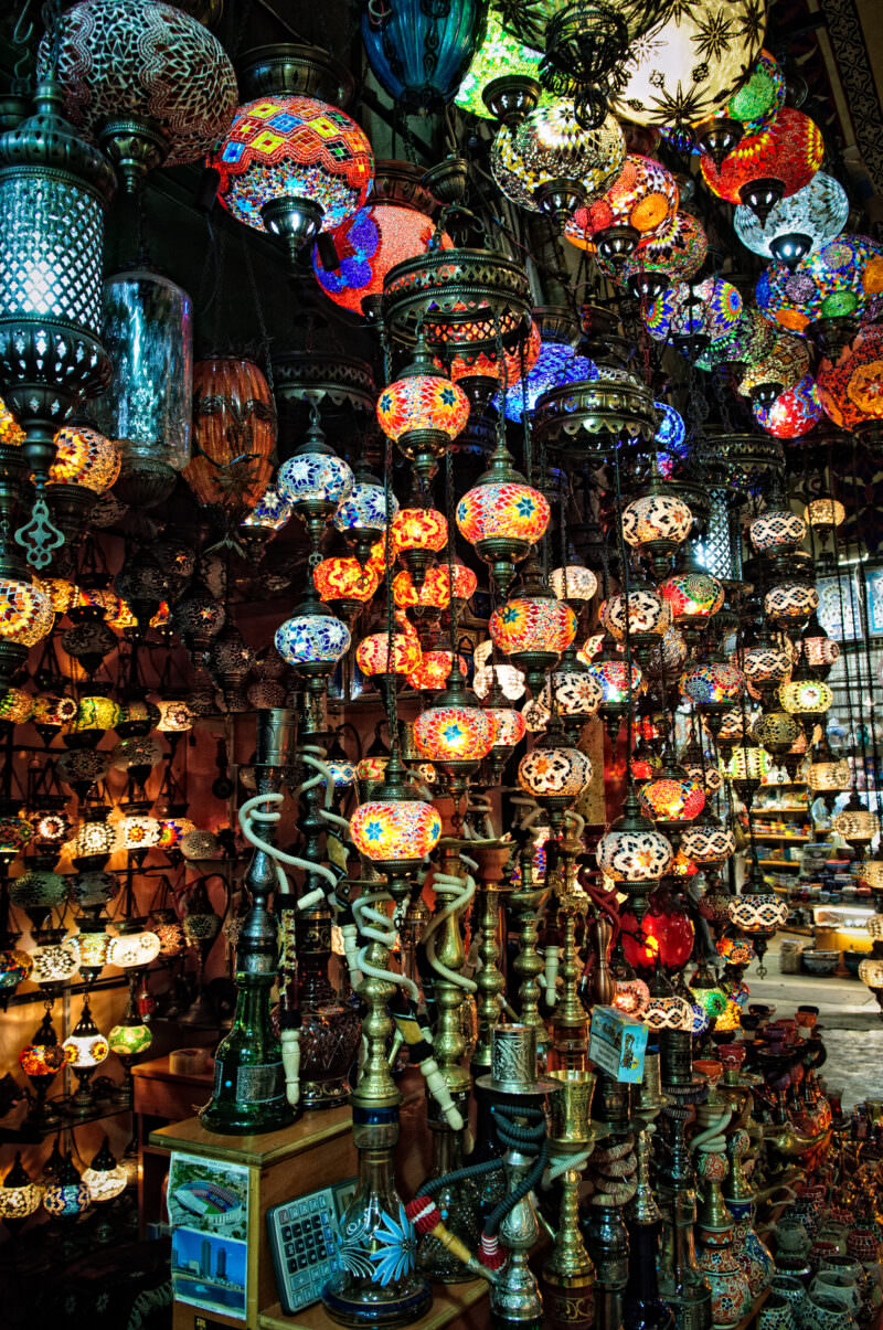 Rows of glowing mosaic glass lamps in reds, blues and golds crowding the ceiling of a Grand Bazaar shop