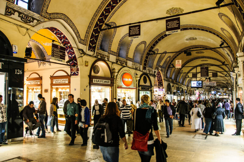 Busy main street of the Grand Bazaar beneath a hand-painted arched ceiling lined with jewelry and gift shops
